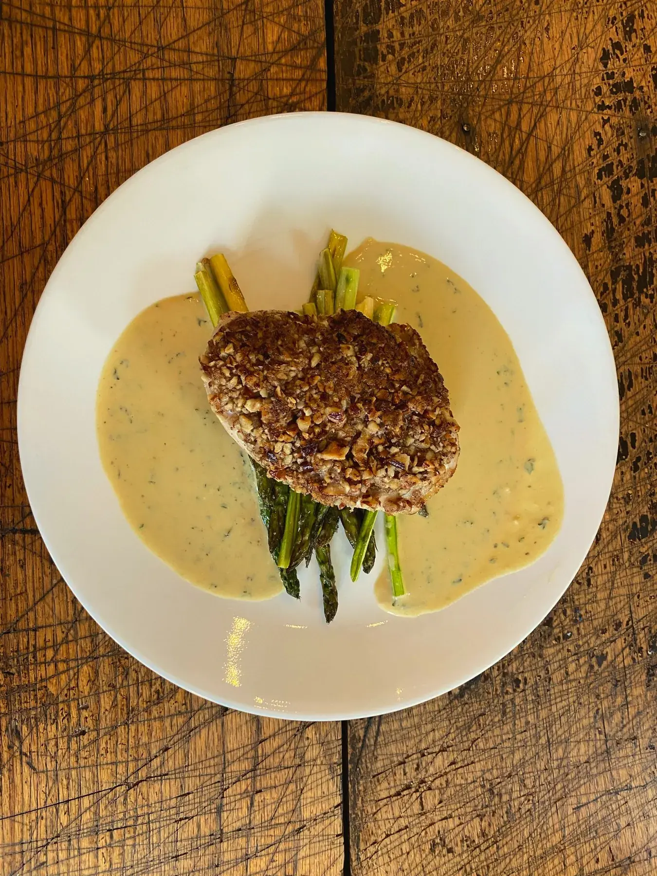 Nut-crusted protein on asparagus with herb cream sauce — organic dining at The Old Ruth