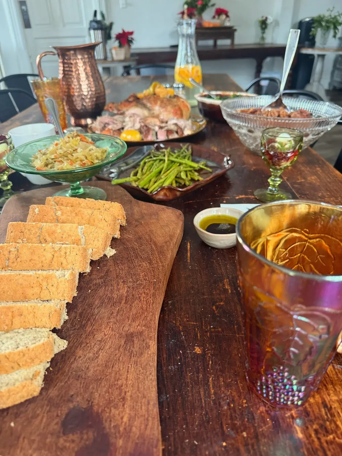 Family-style dinner spread at The Old Ruth — bread board, copper pitcher, asparagus, roasted meat