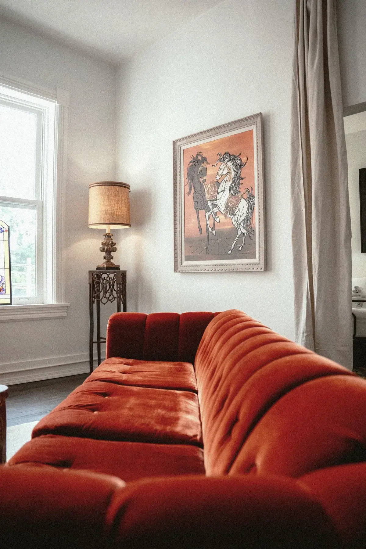 Red velvet sofa with equestrian art in a common room at The Old Ruth