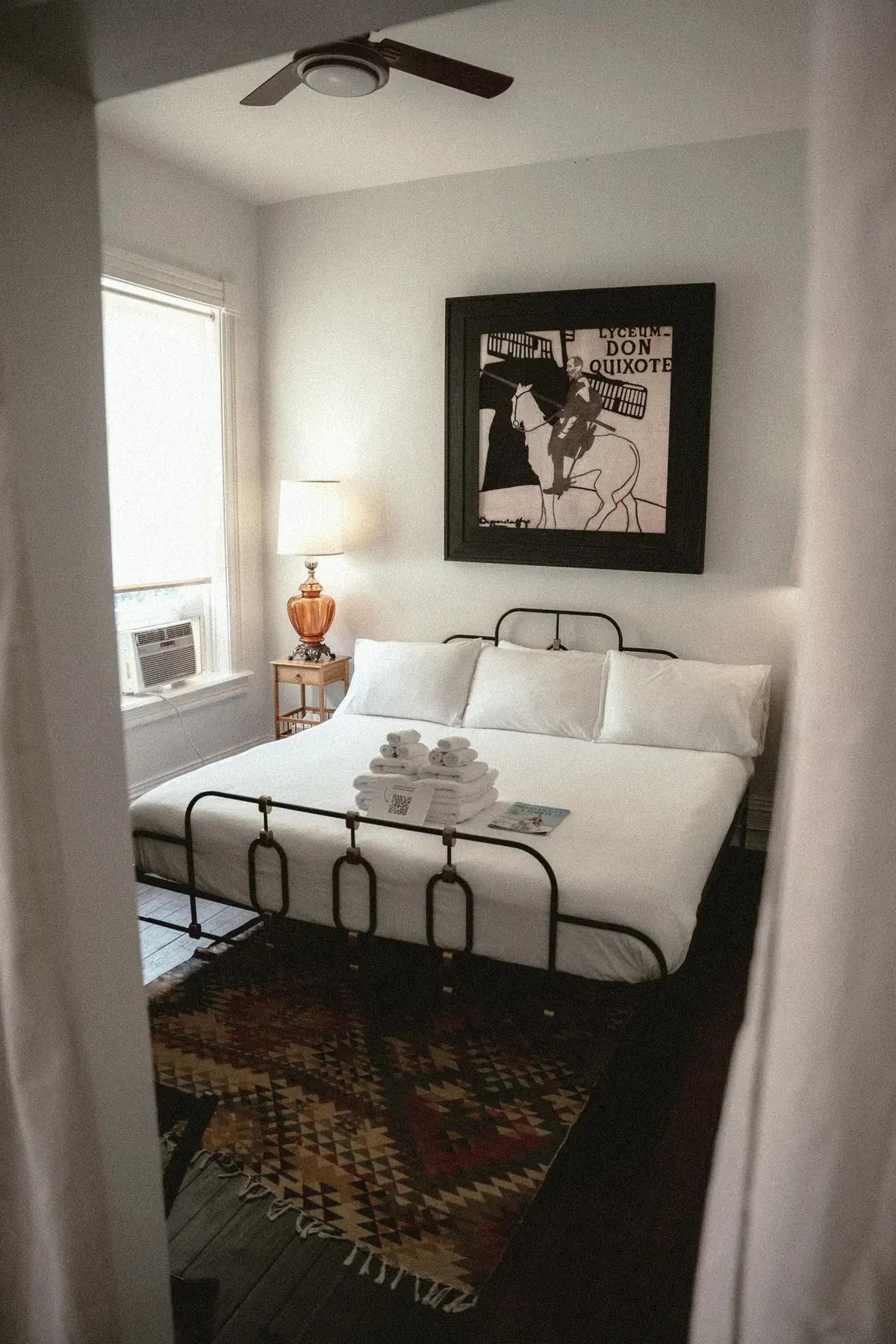 Iron bed with Don Quixote art and curtain framing in an executive suite at The Old Ruth
