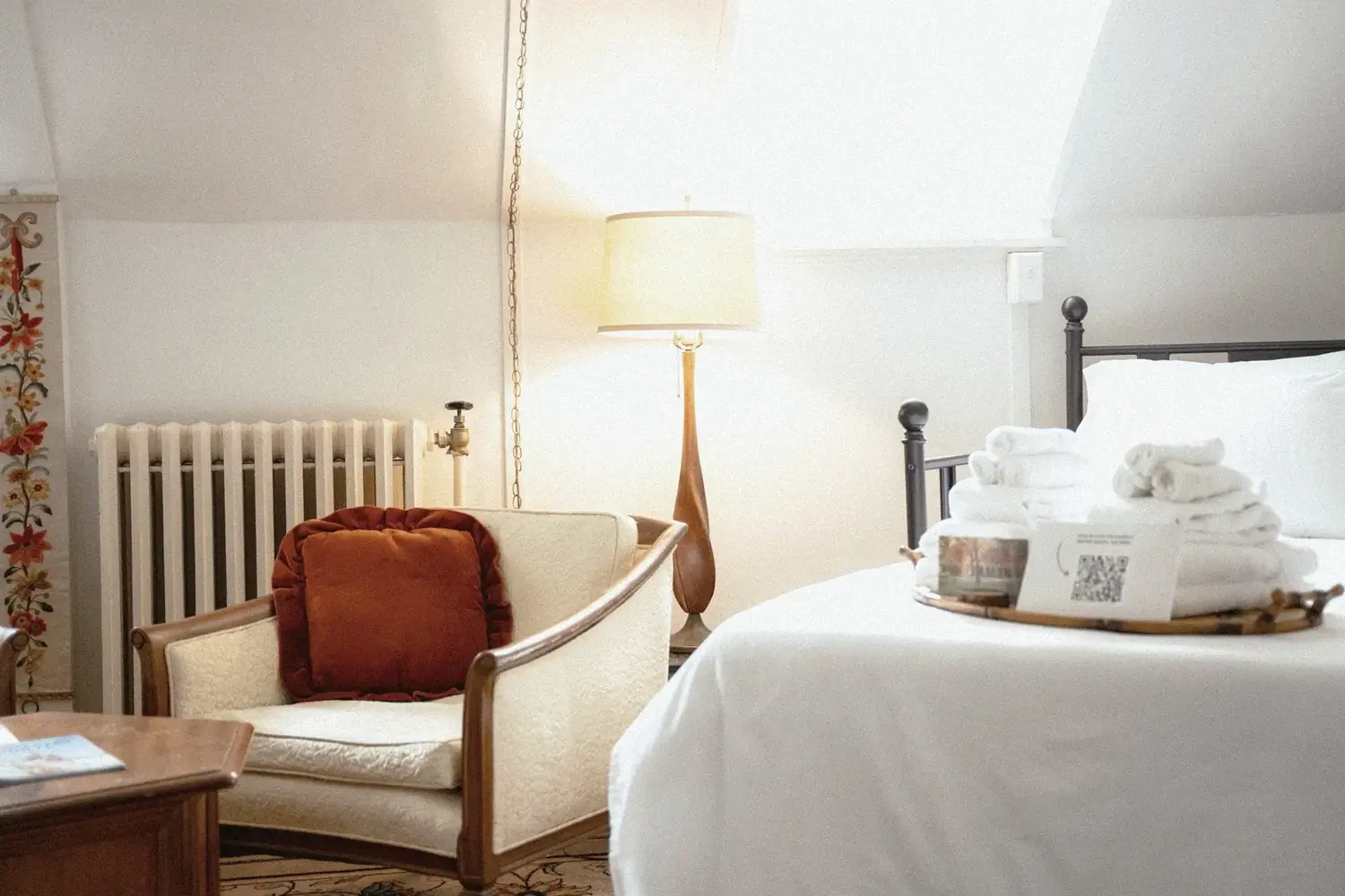 Iron bed with vintage chair, radiator, and warm lamp in a private suite at The Old Ruth