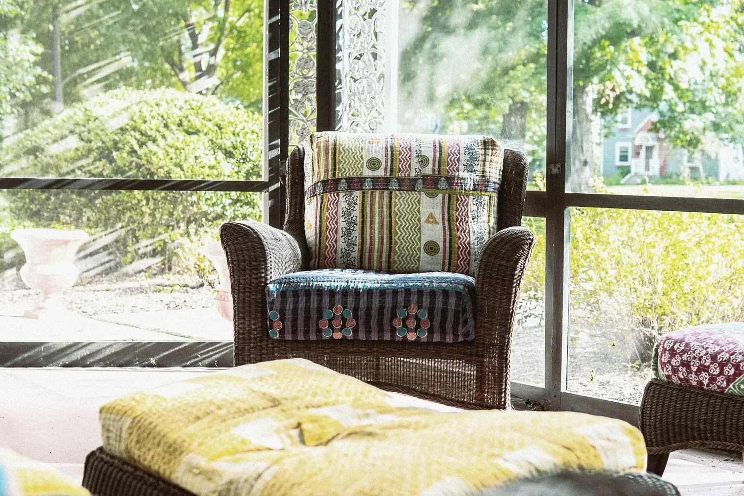 Screened porch at The Old Ruth with wicker chairs and colorful textiles — outdoor living for executive residents